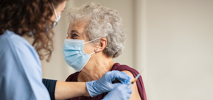 General practitioner vaccinating old patient in clinic